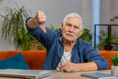 Hoşlanmamak. Mutsuz, son sınıf öğrencisi, işaret parmağı gösteren, hoşnutsuzluğunu dile getiren, evde çalışmaktan memnun olmayan mutsuz bir adam. Memnun olmayan yaşlı büyükbaba masada oturuyor.