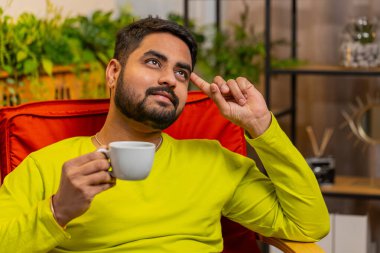 Çekici Hintli bir adam bir fincan sıcak kahve ya da bitki çayı içiyor ve sabahları sallanan sandalyesinde oturuyor. Arap Hindu adam dinleniyor, dinleniyor ve dinleniyor.