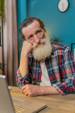 Düşünceli, düşünceli, kıdemli bir adam ofisteki masada dizüstü bilgisayarla ilgili bir sorun düşünüyor. Ciddi büyükbaba, ilham arayışı içinde. Karar vermede fikir yoksunluğu çekiyor. Dikey