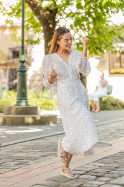 Heyecanlı mutlu kadın gezgin bağırıyor, başarıyı kutluyor, kazanıyor, gol başarısı, iyi haber, piyango talihi, açık havada zafer. Şehir Güneşi Sokağı 'nda yürüyen genç bir bayan. Yaşam Tarzları