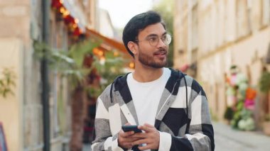 Hintli genç adam sosyal medya uygulamasında akıllı telefon kullanarak kısa mesajlar yazıyor, internette sörf yapıyor, dinleniyor, dışarıda mola veriyor. Şehir caddesinde duran İspanyol turist..