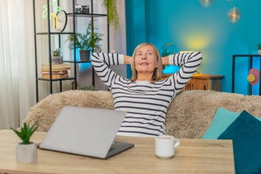 Olgun bir kadın önemli bir görevi tamamladıktan sonra bilgisayarını seve seve kapatır. Kafkasyalı büyükanne evdeki kanepede oturuyor, gülümsüyor ve bir fincan kahve içip keyfine bakıyor.