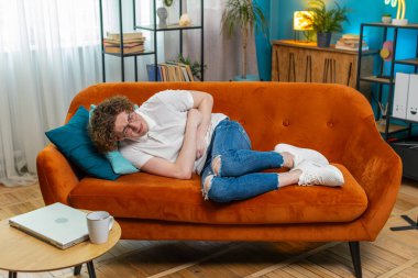 Genç, beyaz bir adam kanepeye uzanmış karın ağrısı ve mide iltihabı şikayeti yaşıyor. Semptom zehirlenmesi geçiren bir adam ishal hazımsızlık peptik ülser pankreatiti geçiriyor..