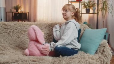 Genç kız evde pelüş tavşanla oynuyor, rahat rahat sohbet ediyormuş gibi yapıyor. Kanepede oturan sarışın çocuk hayal ürünü konuşmaya devam ediyor. Doldurulmuş arkadaşınla nazik bir bağ kurmanın tadını çıkarıyor.