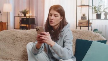 Kanepede oturan genç beyaz kadın hayal kırıklığına uğradı. Akıllı telefona baktı ve bir elini alnına koydu. Kötü haber yüzünden derin bir hayal kırıklığı yaşadı. Evde yetişkin bir kız var..
