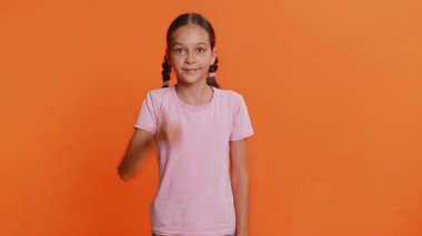 Gibi. Genç ve mutlu bir kız çocuğu kameraya bakıp olumlu bir işaret veriyor, olumlu bir şey, olumlu bir geri bildirim harika bir haber. Stüdyo turuncu arka planda izole çocuklar