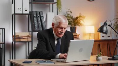 Dizüstü bilgisayar ağı üzerinde çalışan üst düzey mutlu Kafkasyalı işadamı ani zafer, galibiyet, gol başarısı, iyi kariyer haberleri karşısında şok oldu. Heyecanlı serbest çalışan büyükbaba iş yerinde yumruklarını sıkıyor.