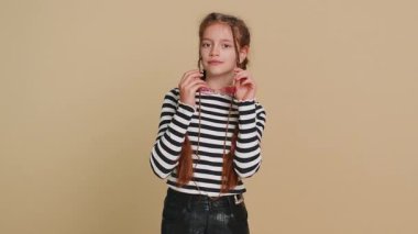 Güneş gözlüğü takan, güzel gülücükler takan, flört eden, gururlu genç kız çocuğunun mutlu portresi. Bej arka planda kapalı alanda izole edilmiş genç çocuklar. İnsan duyguları kavramı