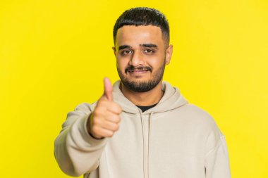 Gibi. Hintli adam bir şeyi onaylıyor ya da olumlu cevap veriyor reklamlar iyi fikir geri bildirimlerini seviyor, başarı zaferini kutluyor. Hintli adam sarı arka planda izole edilmiş.