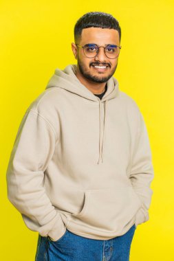 Neşeli, sevimli, mutlu, mutlu, Hintli bir adam gülümseyen, mutlu, mutlu bir yüz ifadesiyle kameraya bakan, dinlenme hayalleri kuran, rahatlatıcı, mutlu bir haber. Sarı arka planda izole edilmiş Arap bir adam. Dikey