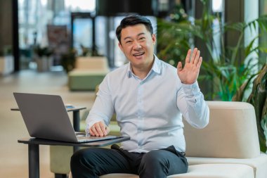 Hoş geldiniz. Mutlu Çinli işadamı el sallayarak selam veriyor. Birine hoş geldin diyor. İnternet ağları, uzaktan konuşma. Modern ofis lobisinde oturan gömlekli girişimci adam..