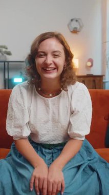 Genç bir kadın saçma sapan anekdotlar, komik şakalar duyduktan sonra yüksek sesle gülüyor, kaygısız bir şekilde eğleniyor, evde pozitif insanların yaşam tarzını yaşıyor. Oturma odasında kanepede çekici bir kız. Dikey.