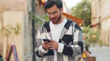 Hintli genç adam sosyal medya uygulamasında akıllı telefon kullanarak kısa mesajlar yazıyor, internette sörf yapıyor, dinleniyor, dışarıda mola veriyor. Şehir caddesinde duran İspanyol turist..