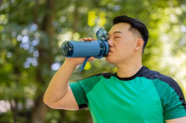 Sportif, atletik, susamış erkek, koşucu, koşucu, parkta çalıştıktan sonra su içen, spor şişesi içen, sağlıklı alışkanlığı olan, Asya yaşam tarzı serinletici su içen,.