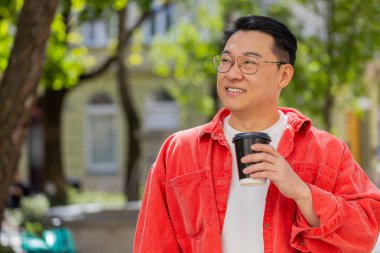 Orta yaşlı mutlu bir Asyalı sabah kahvesinin tadını çıkarıyor sıcak bir şeyler içiyor ve dışarıda gülümsüyor. Dinlenmeye çalışıyorum. Şehir caddesinde yürüyen Çinli adam kahve içiyor. Kasaba yaşam tarzları. Yatay