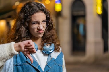 Hoşlanmamak. Mutsuz genç kız işaret dilini gösteriyor, hoşnutsuzluğunu dile getiriyor tatminsiz kötü iş hatası. Geceleri şehir caddesinde gezen hoşnutsuz genç bir kadın. Kopyalama alanı