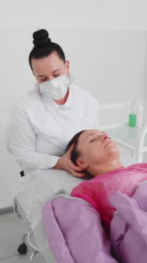 Kozmetik uzmanı doktor presoterapi tedavisi uyguluyor ve kadın hastalara elle masaj yapıyor. Şişkinlik ve selülite karşı mücadelede kullanılan donanım kozmetolojisi tekniği