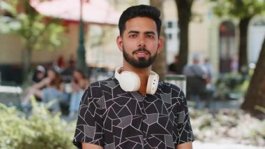 Gibi. Mutlu Hintli genç turist kameraya onaylı bir şekilde bakıyor. İşaret işareti, olumlu geri bildirim gösteriyor. Şehir parkında genç bir İspanyol erkek. Şehir yaşam tarzları açık havada.