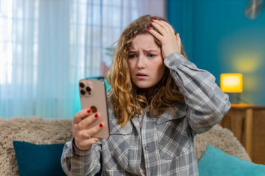 Elinde cep telefonu olan genç bir kadın kötü haber okuduktan sonra üzgün ve hayal kırıklığına uğramış. Kanepedeki beyaz saçlı kız hayal kırıklığına uğramış görünüyor, duygusal tepki, duygusal ifade