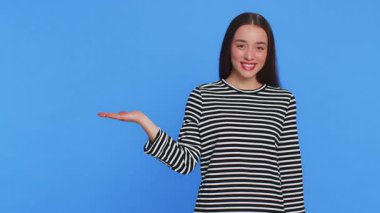 Beyaz tenli güzel bir kadın reklam için reklam alanında boş bir yeri işaret ediyor. Ticari metin fotokopisi için. Mavi arka planda izole edilmiş bir kız. Yaşam biçimi