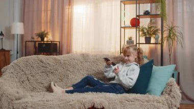 Genç kız ev televizyonunun sesini yükseltti, uzaktan kumandalı çizgi filmleri açtı ve mutlu bir şekilde sallandı. Kanepedeki sarışın çocuk, neşeli, neşeli bir dansla hoplayıp zıplayan karakterleri taklit ediyor.