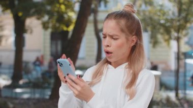 Akıllı telefon daktilosu kullanan beyaz bir kadın aniden piyango sonuçlarını, kötü haberi, servet kaybını ve başarısızlığı kaybediyor. Şehir caddesinde duran turist kız. Kasaba yaşam tarzları.