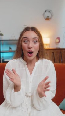 Aman Tanrım, vay canına. Genç bir kadın büyük gözlerle kameraya bakarken şaşkınlığa uğradı. Ani bir zafer, iyi bir galibiyet haberi, evde kutlama. Oturma odasında kanepede oturan heyecanlı kız. Dikey