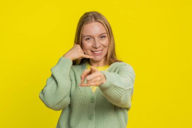 Ara beni, bu iletişim numarası. Beyaz, orta yaşlı, olgun bir kadın kameraya bakıyor. Telefon jesti yapıyor, konuşmak istiyor. Çevrimiçi hizmet teklifi ilanı sarı arka planda