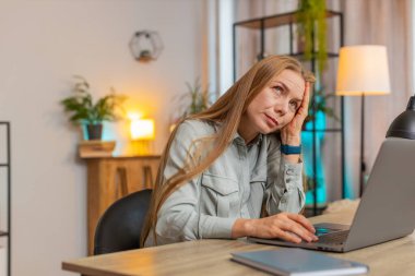 Sıkılmış üzgün, yorgun, yorgun, yorgun, Kafkasyalı, serbest çalışan, yorgun, motivasyonsuz, kadın yönetici sıkıcı bir dizüstü bilgisayar işi, ev ofis masasında yorgun düşme sıkıntısı..