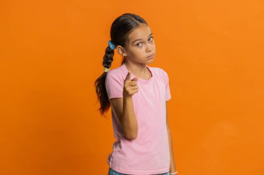 Genç kız çocuk parmağını sallıyor ve hayır diyor, dikkatli ol, tehlike hatasından kaçınmak için azarlıyor ve tavsiye veriyor, onaylamamak, katılmamak, hoşlanmamak. Turuncu arka planda ergen çocuklar