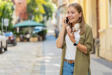Telefon, iyi haber, dedikodu. Akıllı telefonda hoş sohbetler yapan mutlu, beyaz bir bayan, dışarıda arkadaşlarıyla konuşmaktan zevk alıyor. Şehir caddesinde duran kız. Kasaba yaşam tarzları.