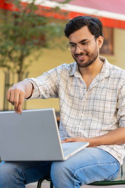 Sandalyede oturan Hintli serbest yazar dizüstü bilgisayarını açar teneffüste internet üzerinden iş arama web sitesinde sohbet etmeye başlar. Genç adam netbook ekranına bakıyor, mesajlar gönderiyor, film izliyor..