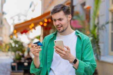 Kafkasyalı bir adam internet üzerinden alışveriş yapmaya çalışırken kredi kartı bloke edilmiş cep telefonuyla şok olmuş. Sokaktaki kızgın erkek turist bankanın reddetme sorununu satın alıyor ödeme eksikliği para dengesi