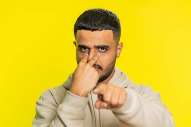 Gözüm üzerinde. Gözlerine ve kamerasına bakan özgüvenli adam, seni birini gözetlerken izlediğimi göster. Yakışıklı, hayal kırıklığına uğramış Hintli adam sarı stüdyo arka planında izole edilmiş.