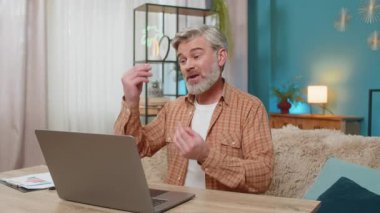 Beyaz, olgun bir adam önemli bir iş kamerası görüşmesi yapmak için dizüstü bilgisayar kullanıyor. Adam ciddi odaklanmış görünüyor, tartışma sırasında aktif hareket ediyor, internetten video görüşmesi.