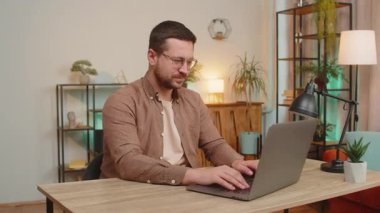 Gibi. Laptop kullanan mutlu, genç, beyaz bir adam kameraya bakıp olumlu işaret veriyor. İyi haber, olumlu geri bildirim. İş adamı ofis masasında oturuyor.