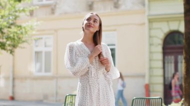 Düşünceli gülümseyen, düşünceli, mutlu, genç, yetişkin bir kadın. Çözüm üzerinde kafa yoran, soru soran, ilham veren açık havada rüya gören. Güneşli şehir sokağındaki güzel kız. Kasaba yaşam tarzları.