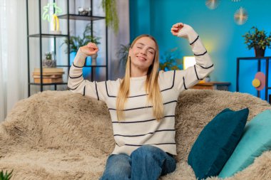 Stresli bir iş gününden sonra dinlenen beyaz kadın kanepede uzanmış gülümsüyor. Sessizliğin tadını çıkarıyorum. Rahatlıyorum. Kapalı mekanda rahatlıyorum.