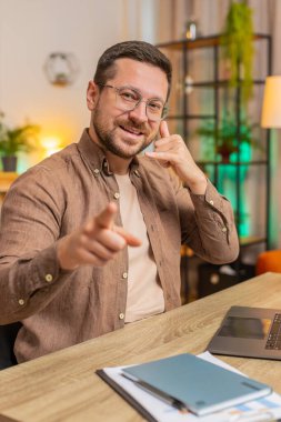 Beni ararsın. Genç Kafkasyalı patron iş adamı dizüstü bilgisayarını kullanarak telefon görüşmesi yapmak istiyor, bana işaret veriyor, online randevu. Ofisteki serbest çalışan adam oturma odasındaki kameraya bakıyor..