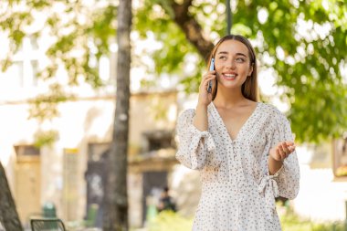 İyi haber dedikoduları. Akıllı telefonda güzel sohbetler yapan mutlu beyaz kadın dışarıda arkadaşınla sohbet etmekten zevk alıyor. Şehir caddesinde duran gezgin kız. Kasaba yaşam tarzları