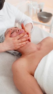 Kozmetik uzmanı özel nemlendirici krem uyguluyor, güzel beyaz bir kadının yüzünü ovuyor, soyuyordu. Güzellik salonunda yüz bakımı yaşlanmayı önleyen kozmetik masaj prosedürü. Güzellik tedavisi