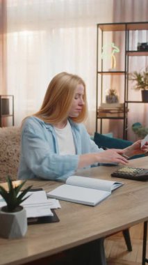 Kadın evde harcamaları düzenler, rakamları not defterine yazar ve faturaları sabırla onaylar. Masadaki beyaz kız, finans için berraklık ve dikkatli strateji birleştirme hesap makinesi kullanıyor