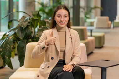 Gibi. Mutluluktan havalara uçan genç beyaz kadın zafer başarısını kutluyor. Ofis lobisinde oturan parmaklarını gösteren kameraya bakıyor. Otel salonundaki resmî kız çalışanın portresi..