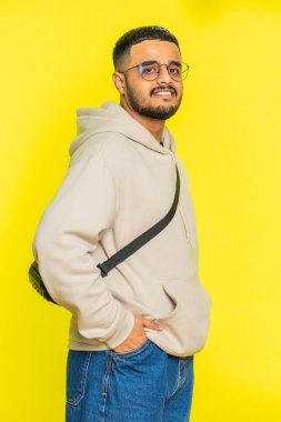 Neşeli, sevimli, mutlu, mutlu, Hintli bir adam gülümseyen, mutlu, mutlu bir yüz ifadesiyle kameraya bakan, dinlenme hayalleri kuran, rahatlatıcı, mutlu bir haber. Sarı arka planda izole edilmiş Arap bir adam. Dikey