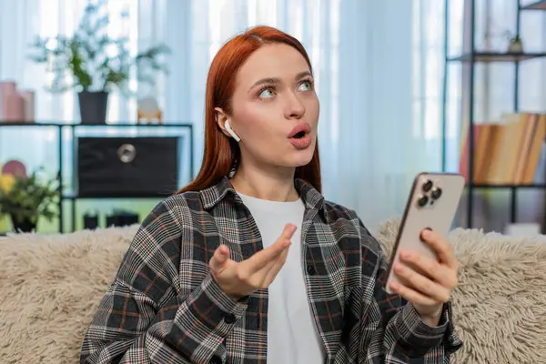 Evdeki genç kadın mobil uygulama kullanarak yeni bir dil öğreniyor ve kelimeleri odaklanma ve neşeyle yüksek sesle tekrarlıyor. Kanepedeki beyaz saçlı kız eğitim sürecinin tadını çıkarıyor. Telaffuz ve konuşma pratiği yapıyor.