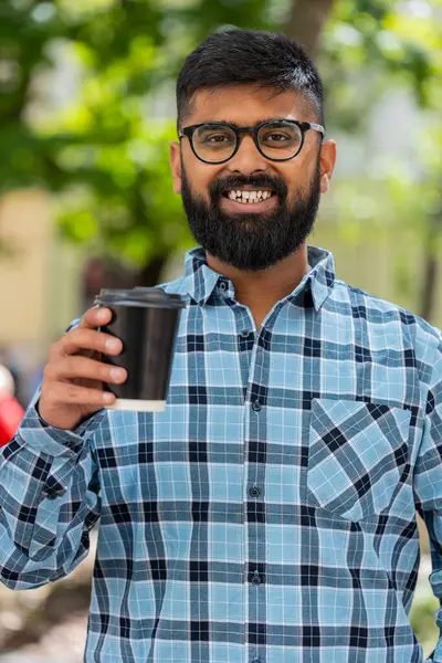 Mutlu Hintli sakallı adam sabah kahvesinin tadını çıkarıyor sıcak bir şeyler içiyor ve dışarıda gülümsüyor. Dinleniyorum, ara veriyorum. Şehir caddesinde dikilen İspanyol adam kahve içiyor. Kasaba yaşam tarzları. Dikey