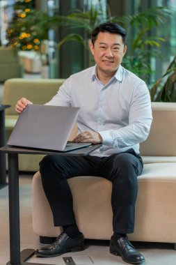 Çinli genç iş adamı otel lobisindeki işi bitirdikten sonra dizüstü bilgisayarı kapatıyor. Gülümseyen yönetici internette çalışıyor, uzaktan kumandayla. E-öğrenme, internette gezinme, netbook 'ta kameraya bakma..