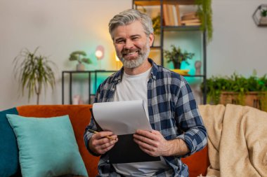 Günlük kıyafetlerle gülümseyen, sakallı, olgun bir adam. Belgeleri inceleyen, iş gazetelerini okuyan, mali raporları hazırlayan. Kafkasyalı yaşlı adam kanepedeki ani zaferle şok oldu..