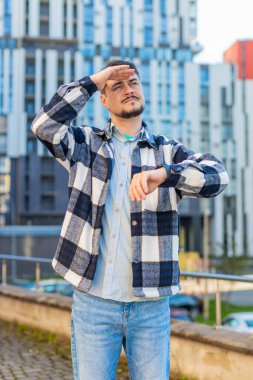 Ofisin dışında dikilip iş yerinde sabırsız bir adamla buluşmayı bekleyen üzgün bir işadamı. Kol saati kontrollerine hoşnutsuz bakıyor. Geç kalma konseptinden rahatsız oluyor..