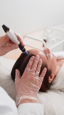 Alopecia. Beyaz kız saç restorasyonu sırasında sakince yalan söylüyor. Kozmetik uzmanı modern klinikte saç dökülmesini canlandırmak ve mücadele etmek için dermapen mikronedling ve enjeksiyon terapisi uyguluyor.